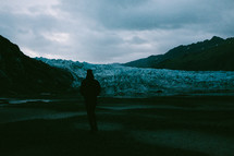 a man walking towards a glacier 