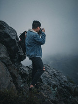 a man taking a picture from a mountaintop 
