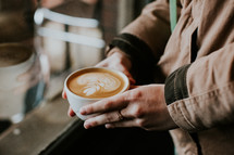 a woman holding a coffee cup with creamer 