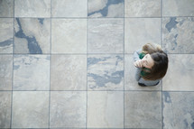 Aerial view of woman standing on tile in prayer.