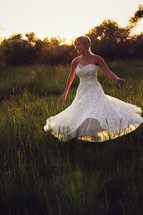 Woman in a white dress twirling in a field of tall grass.