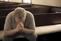 a man praying alone in a church 