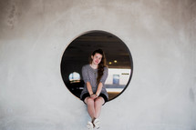 portrait of a teen girl sitting in a port hole window 