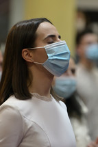 a woman in a mask at a worship service 