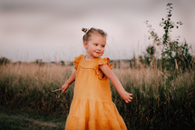 a happy little girl in an orange dress 