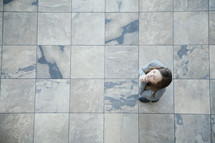 Aerial view of woman standing on tiles in prayer.