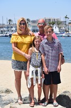 a family portrait in front of yachts in a Harbor in Newport Beach, California 
