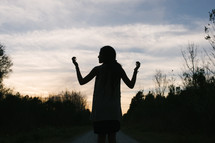 silhouette of a young woman with raised hands 