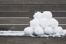 a stack of snowballs on a bench 