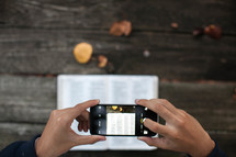 a man taking a picture of Bible scripture with his cellphone 