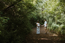 expecting couple standing on a trail holding hands 