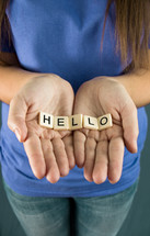 A girl holds out the word "HELLO"