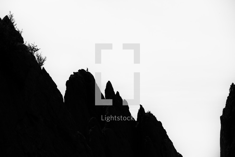 Silhouette of a person climbing a huge mountain in black and white