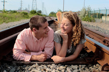 Couple laying on a railroad track.