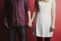 A couple holding hands with a red background
