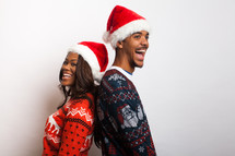 couple in ugly Christmas sweaters and santa hats