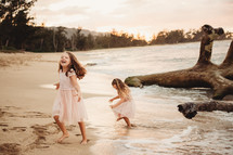 children running on a beach in fancy dresses 