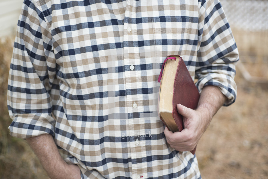 a man in a plaid shirt holding a Bible 