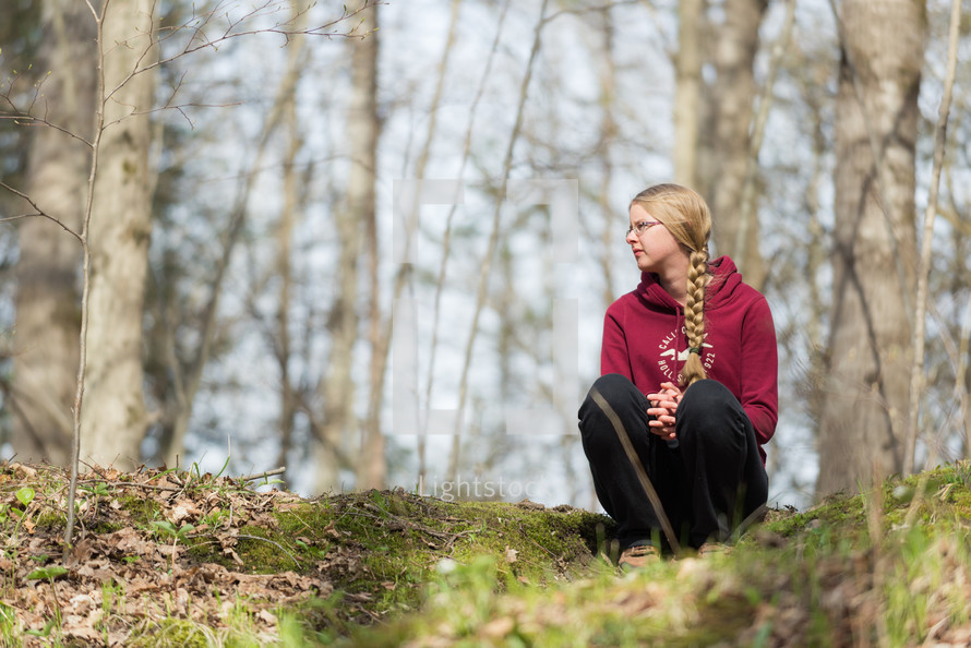 Woman sitting on a hill in the woods.