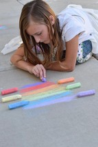 a child drawing a rainbow with sidewalk chalk 