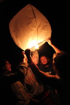 friends lighting a floating paper lantern 
