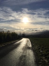 sunlight on a wet rural paved road 
