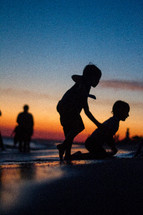 Kids playing on the beach at sunset