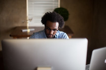 An African American man sitting at a desk typing on a computer 