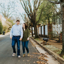 couple holding hands walking down a neighborhood street 