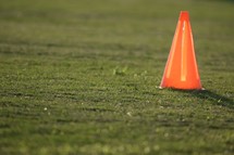 glowing orange cone on a soccer field at sunset  