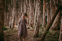 a child in a dress walking in a forest 