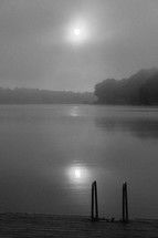 light of the full moon through the clouds over a lake and dock 