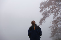 a woman walking in dense fog 