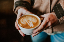 woman holding a cup of coffee with creamer