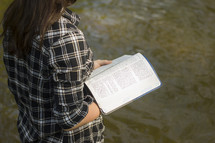 Woman reading the Bible outside.