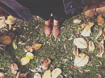 shoes standing in grass and fall leaves 