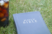 Bible and drink on grass 