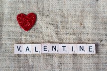 a red glittery heart and word Valentine in scrabble pieces on burlap 