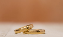 Macro View of Wedding Rings on a Wooden Table with orange Background