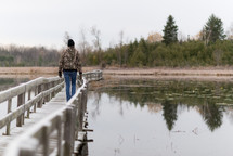 man walking across a bridge over a lake 
