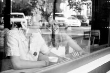 a couple sitting in a window of a coffee shop 