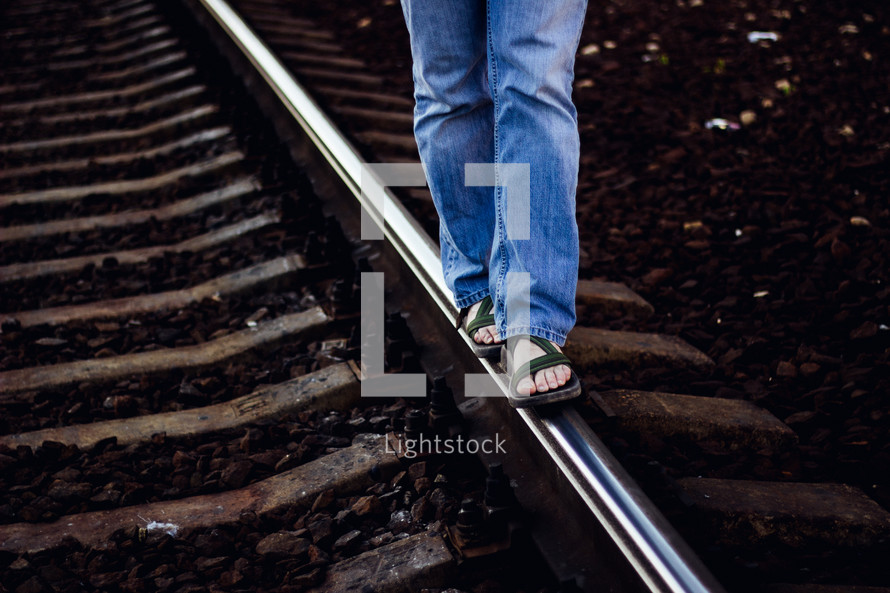 A person walking a rail along a railroad track.