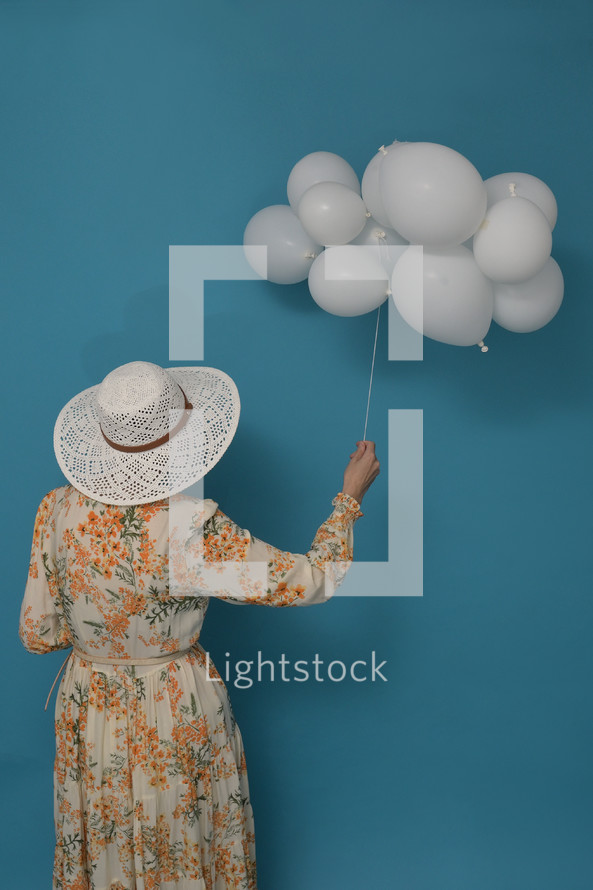 Cloudy day. Concept with woman and white balloons against blue sky