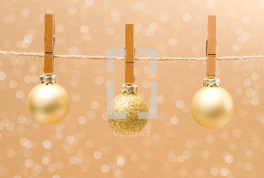 gold Christmas ornaments hanging with clothespins 