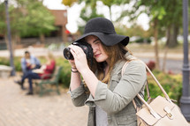 a woman in hat taking a picture with a camera 