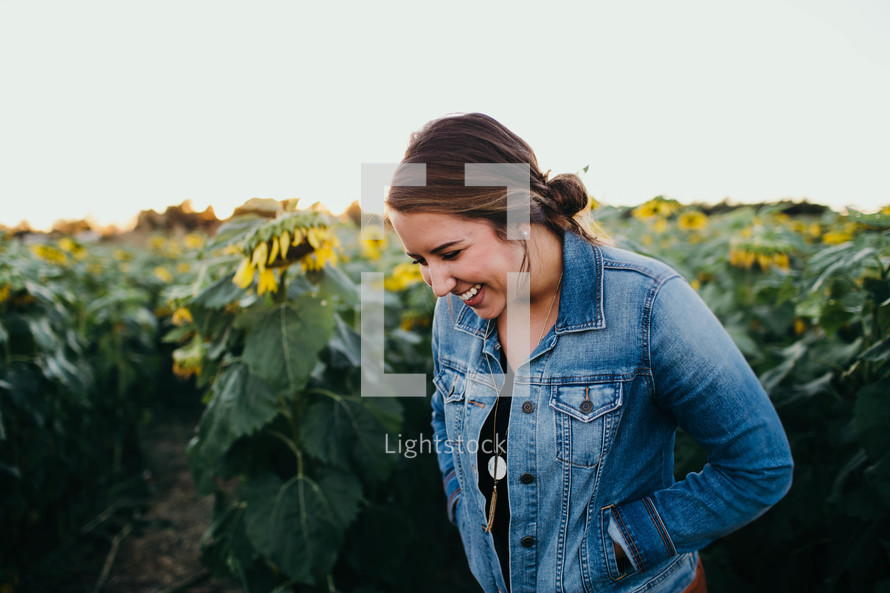 a woman laughing standing in a field of sunflowers 