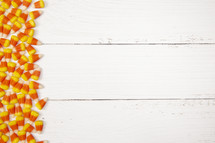 candy corn border on white wood background 