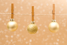 gold Christmas ornaments hanging with clothespins 