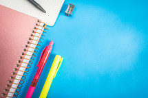 Different kind of school/office supplies for studying, on a blue background. Back to school.