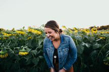 smiling young woman standing in a field of sunflowers 